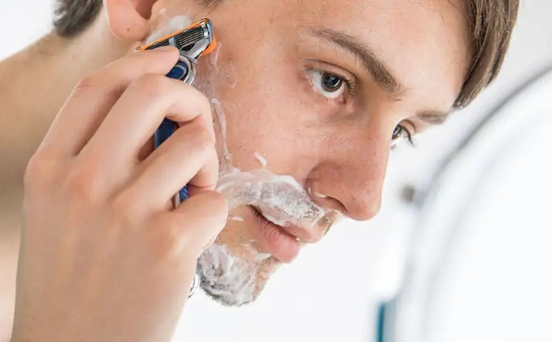 Man shaving his cheek with a manual cartridge razor